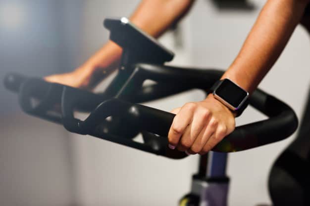 woman gym doing spinning cyclo indoor with smart watch 1139 1716